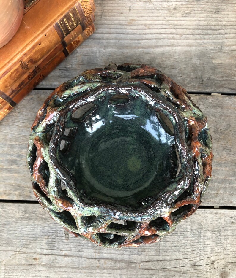May include: A ceramic bowl with a green glaze and a brown, twig-like design. The bowl is handmade and has a unique, rustic look.