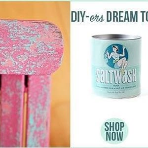May include: A close-up of a pink wooden surface with a blue paint effect. The surface is textured and has a distressed look. The image also shows a can of paint with the words "Saltwash" and a woman in a vintage dress on the label. The can is blue and white with a red circle around the word "Saltwash".