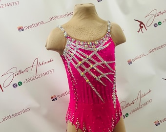 May include: A pink leotard with a white design featuring rhinestones and a silver trim. The leotard has a scoop neck and a low back.