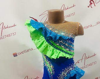 May include: A blue and green leotard with a ruffled design, embellished with rhinestones. The leotard has a sheer mesh neckline and is displayed on a mannequin. The Instagram handle @svetlana__ is visible.