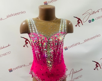 May include: A vibrant pink leotard for rhythmic gymnastics, adorned with sparkling rhinestones and crystals. The bodice features a sheer nude mesh, and the straps are embellished with shimmering details. The design includes the text "Svetlana Alekseenko" and a phone number.