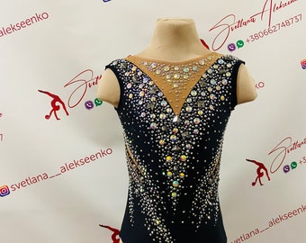 May include: Black leotard with a sheer mesh panel and a V-shaped neckline. The leotard is decorated with rhinestones and sequins.