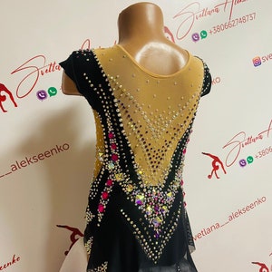 Pu&ograve; includere: Un body nero e bianco con schiena e maniche in rete nude trasparente. Il body &egrave; impreziosito da strass e gemme colorate. Il design presenta un motivo a forma di V sul davanti e sul retro, con una gonna bianca.