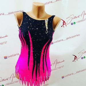 Può includere: Un body nero e rosa con strass. Il body ha un corpetto nero e una gonna rosa con fiamme nere. Il body è su un manichino.