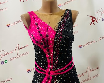 Può includere: Un body nero e rosa con strass e un nastro rosa. Il body ha un pannello in rete nera sul davanti e un pannello in rete rosa sul retro. Il body è progettato per la ginnastica o la danza.