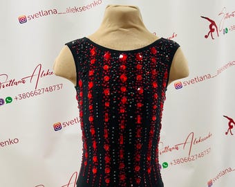 May include: A black leotard featuring red and black embellishments. The sleeveless garment is decorated with red rhinestones and black accents, creating a sparkling design. The leotard is displayed on a mannequin.