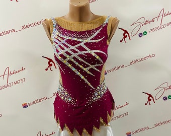 Può includere: Un body color borgogna con un design geometrico bianco e oro. Il body ha una gonna bianca attaccata alla parte inferiore. Il body è decorato con strass.