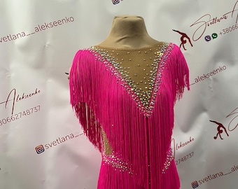 Può includere: Un body rosa con frange e strass. Il body ha una scollatura a V e maniche corte. Le frange sono sulle spalle, sul davanti e sul retro del body.