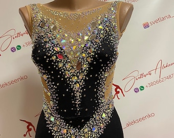May include: A black leotard with a sheer mesh neckline and a V-shaped design adorned with iridescent rhinestones. The leotard is on a mannequin and has a sleeveless design.