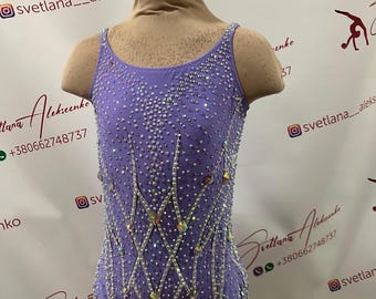 May include: A lavender leotard for gymnastics or dance, adorned with sparkling rhinestones. The sleeveless garment features a scoop neckline and a decorative pattern of intersecting lines. The leotard is displayed on a mannequin.