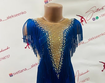 May include: A blue leotard with fringe and rhinestones. The leotard has a V-neck and a scoop back. The fringe is blue and the rhinestones are clear. The leotard is on a mannequin.