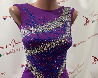 May include: A sleeveless, purple leotard with intricate embellishments. The bodice features a pattern of blue lines and is adorned with numerous sparkling rhinestones. The leotard is displayed on a mannequin.