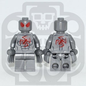 Peut inclure: Une figurine Lego argentée avec des yeux rouges et un motif d'araignée rouge sur la poitrine et le dos. La figurine est debout sur une surface blanche.