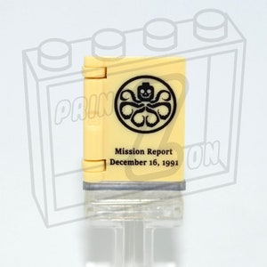 Könnte beinhalten: Ein gelber LEGO-Stein mit einem schwarzen Aufdruck eines Hydra-Logos und dem Text "Mission Report December 16, 1991".