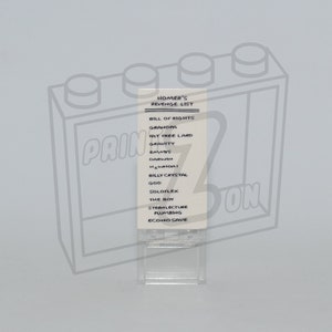 May include: A white card with black text listing "Homer's Revenge List: Bill of Rights" and a list of items including "Grandpa", "Fat Free Lard", "Gravity", "Saw", "Billy Crystal", "God", "Soloflex", "The Boy", "Sterflecture", "Plumbing", and "Econo Save".