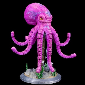May include: A vibrant, pink octopus sculpture with segmented tentacles and a detailed head. The sculpture features a yellow eye and blue accents. It stands on a round base with an anchor and seaweed details, set against a black background.