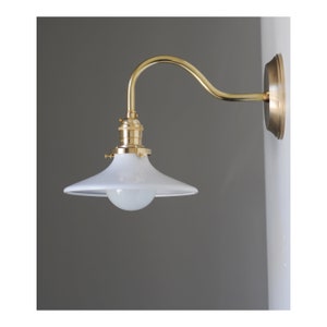 Hardwired, Unlacquered brass sconce with 8” curved arm. Black or White porcelain enamel shade.