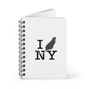 May include: A white spiral-bound notebook featuring a black graphic of a rat replacing the heart symbol in the text I NY. The rat has a long pink tail that curves underneath it, and the notebook is shown from a slightly angled perspective.