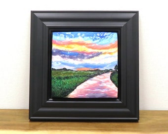 Pink river wall art made with polymer clay. This small, framed artwork depicts a colourful sunset over a river and has a Christian theme