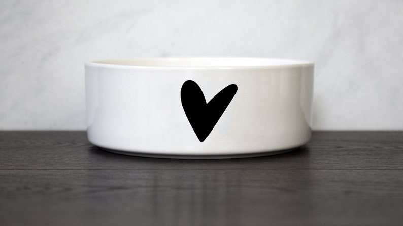 Puede incluir: Taz&oacute;n de cer&aacute;mica blanco para mascotas con un dise&ntilde;o de coraz&oacute;n negro.