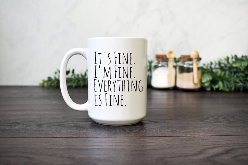 May include: White ceramic coffee mug with black text that reads "It's fine. I'm fine. Everything is fine."
