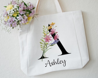 May include: White canvas tote bag with a black letter A decorated with watercolor flowers and the name Ashley printed below.