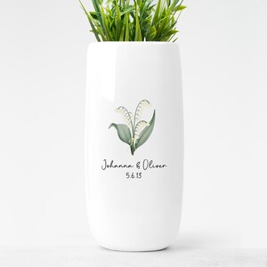 May include: White ceramic vase with a green and white lily of the valley illustration and the text "Johanna & Oliver 5.6.13"