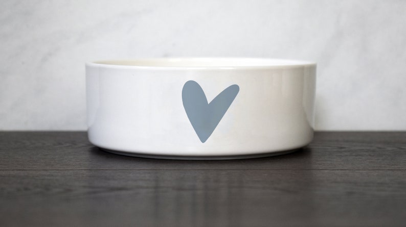 Puede incluir: Taz&oacute;n de cer&aacute;mica blanco para mascotas con un dise&ntilde;o de coraz&oacute;n azul claro.