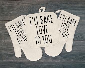 May include: Set of three beige oven mitts with black text that reads "I'll bake love to you".