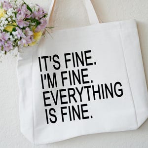 May include: White canvas tote bag with black text that reads "It's fine. I'm fine. Everything is fine."