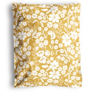 May include: Mustard yellow shipping mailer with a white floral pattern. The design features various sizes of flowers and leaves, creating a repeating pattern across the surface. The mailer is sealed and ready for shipping.