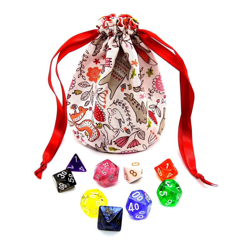 May include: A drawstring dice bag with a whimsical pattern of animals and flowers in shades of red, pink, and gray. The bag is tied with bright red ribbons. Assorted polyhedral dice in various colors, including black, pink, and green, are scattered around the bag.