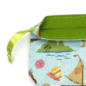 May include: A small drawstring bag with a tropical island pattern in shades of blue, green, and tan. The bag has a green satin ribbon drawstring and a green interior lining. The bag features illustrations of palm trees, boats, and flowers.