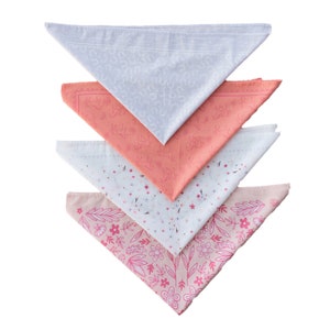 May include: Four cotton bandanas in a stack. The top bandana is light gray with a white pattern. The second bandana is coral with a white pattern. The third bandana is white with a small pink floral pattern. The bottom bandana is pink with a larger pink floral pattern.