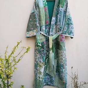 Könnte beinhalten: Eine lange grüne und weiße Patchwork-Robe mit einem Bindegürtel. Die Robe ist aus gestepptem Stoff und hat einen traditionellen japanischen Stil.