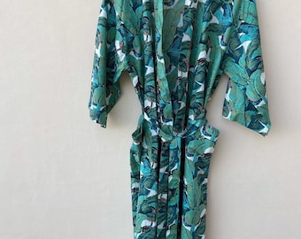 May include: A green and white robe with a tropical leaf print. The robe has a tie belt and long sleeves.