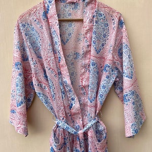 Puede incluir: Una bata de color blanco, azul y rosa con estampado de paisley y cintur&oacute;n de atar. La bata tiene mangas largas y dos bolsillos.