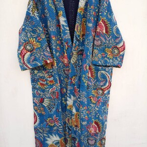 May include: A long, open-front blue robe with a vibrant floral and paisley pattern in red, yellow, and white. The robe has long sleeves and pockets. The interior is a solid navy blue.