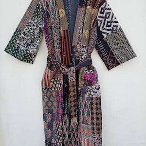 May include: A long, black and multi-colored patchwork robe with a tie belt. The robe is made of cotton and has a quilted design.