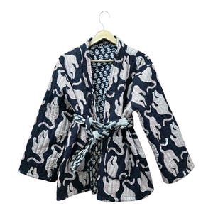 May include: A black quilted jacket with a pink and white animal print. The jacket has a tie belt and long sleeves.