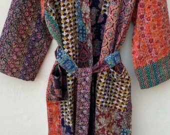Op de afbeelding: Een kleurrijke patchwork-badjas met lange mouwen en een strikceintuur. De badjas is gemaakt van een zachte, comfortabele stof en heeft verschillende bloem- en geometrische patronen.