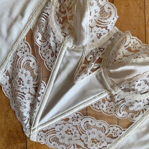 Może przedstawiać: Biała koronka z falbanką. Koronka jest delikatna i ma kwiatowy wz&oacute;r.