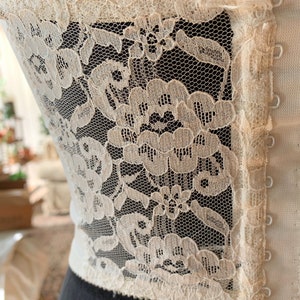 Może przedstawiać: Biały gorset z koronki z zapięciem na haftki i oczka. Koronka jest delikatna i ma kwiatowy wz&oacute;r.