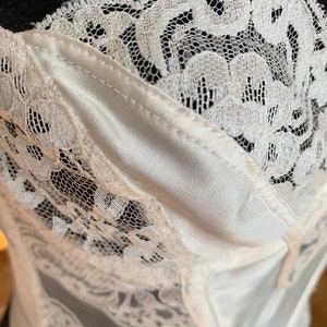 Może przedstawiać: Biały gorset koronkowy z satynową podszewką. Koronka ma kwiatowy wz&oacute;r.