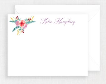 May include: A white stationery card with a floral design in the top left corner. The design features pink, red, and yellow flowers with green leaves. The name "Katie Humphrey" is written in purple cursive script in the top right corner.