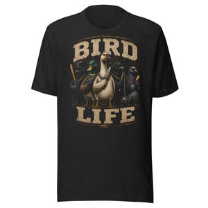 May include: A black short-sleeve t-shirt featuring a graphic print of five birds standing in a row. The central white duck holds a knife, flanked by other birds with baseball bats and a mace. The text BIRD LIFE is printed in a tan, distressed font.