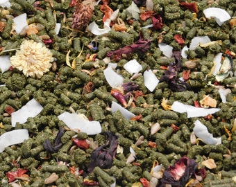 May include: A close-up of a mix of green, brown, and white ingredients. The mixture includes dried flowers, coconut flakes, and small green pellets.