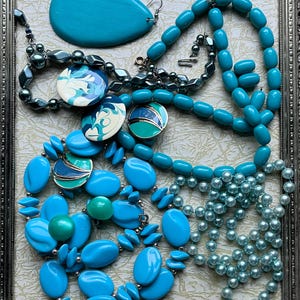 May include: A collection of turquoise and blue necklaces and earrings. The necklaces are made of various materials, including plastic, glass, and metal. The earrings are made of metal and have a turquoise stone.