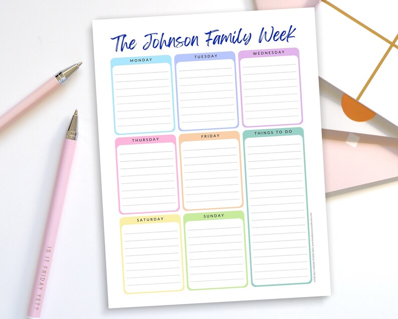 May include: A weekly family planner titled "The Johnson Family Week" with colorful boxes for each day and a "Things to Do" section. Two pink pens are in the image, one with the text "IS IT FRIDAY YET?"