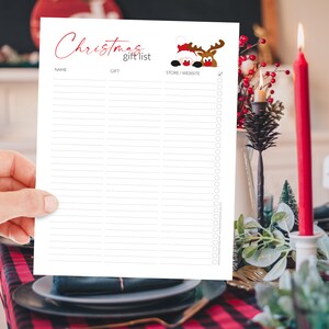 Pu&ograve; includere: Un elenco di regali di Natale bianco con testo rosso e una grafica di Babbo Natale e renne. L'elenco include sezioni per nome, regalo e negozio/sito web. L'elenco &egrave; tenuto in mano.